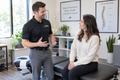 A chiropractor consulting with a female prospective patient in a bright clinic